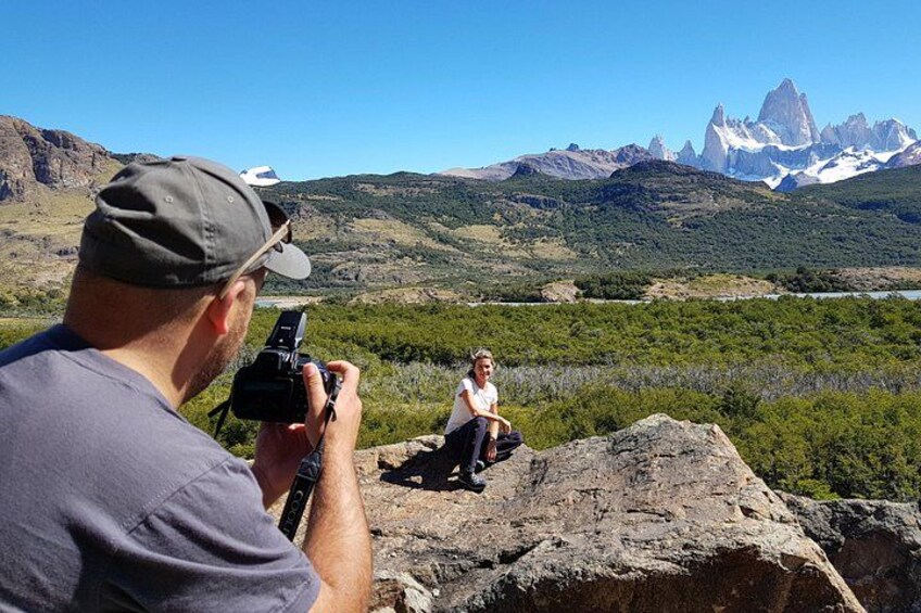 A person taking a photograph of a landscape with mountains and a body of water. 2