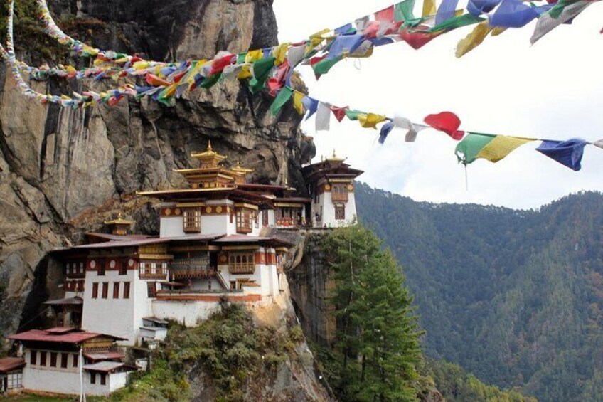 A monastery perched on a cliff with colorful prayer flags. 1