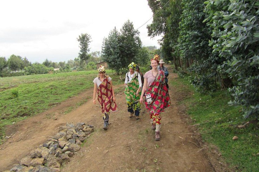 Three people walking on a dirt path surrounded by greenery. 2