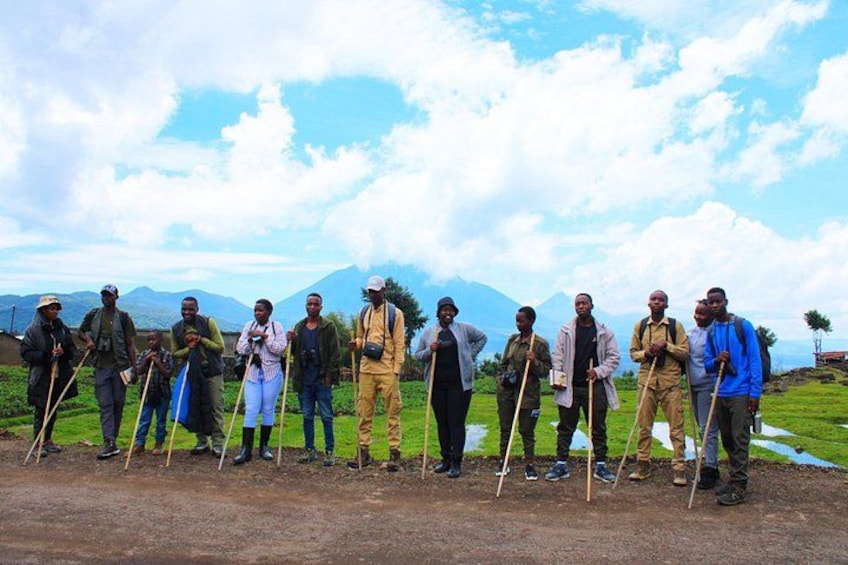 A group of people standing on a dirt path with a mountainous background. 3