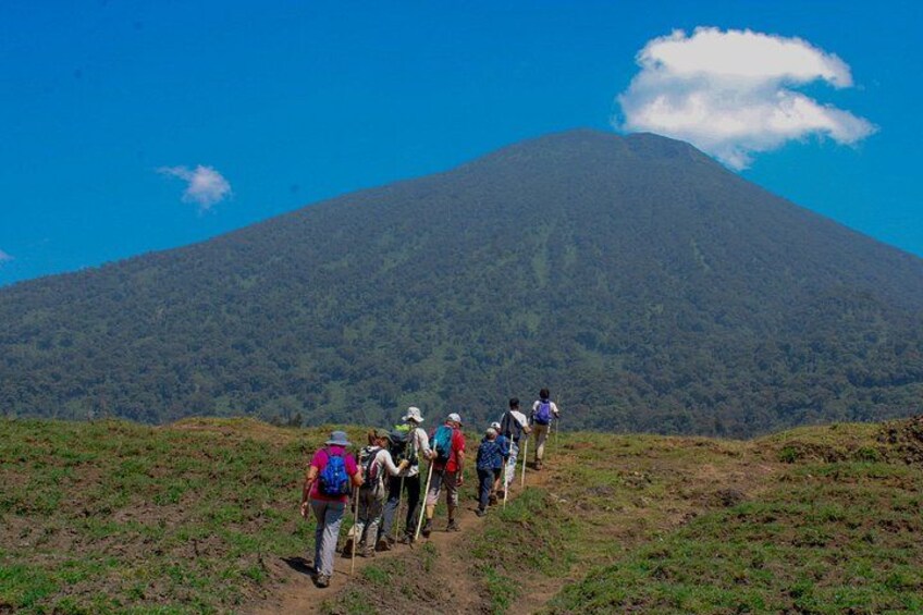 A group of hikers ascending a mountain trail with a volcano in the background. 1