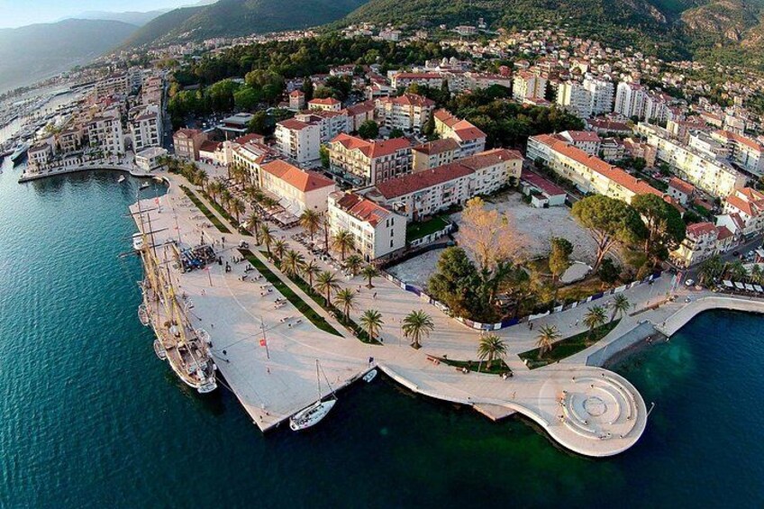 An aerial view of a coastal town with a marina, buildings, and a promenade. 2