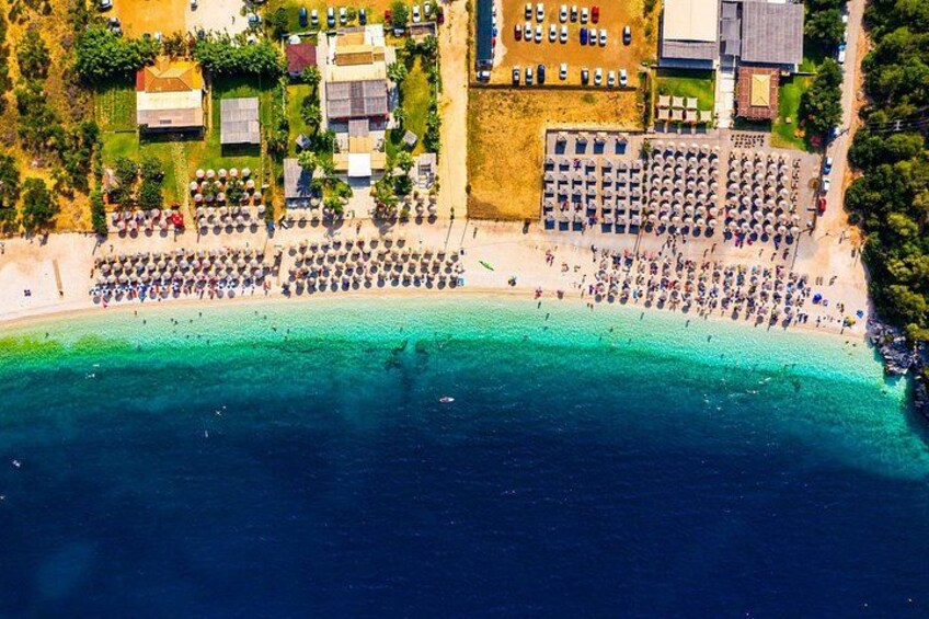 An aerial view of a beach with umbrellas, cars, and buildings. 3