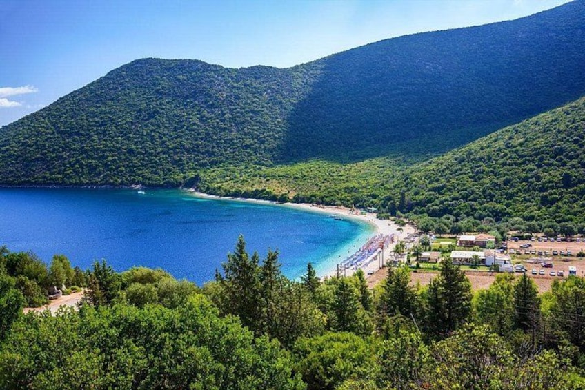 A coastal landscape with a beach, a mountain, and a clear blue sea. 1