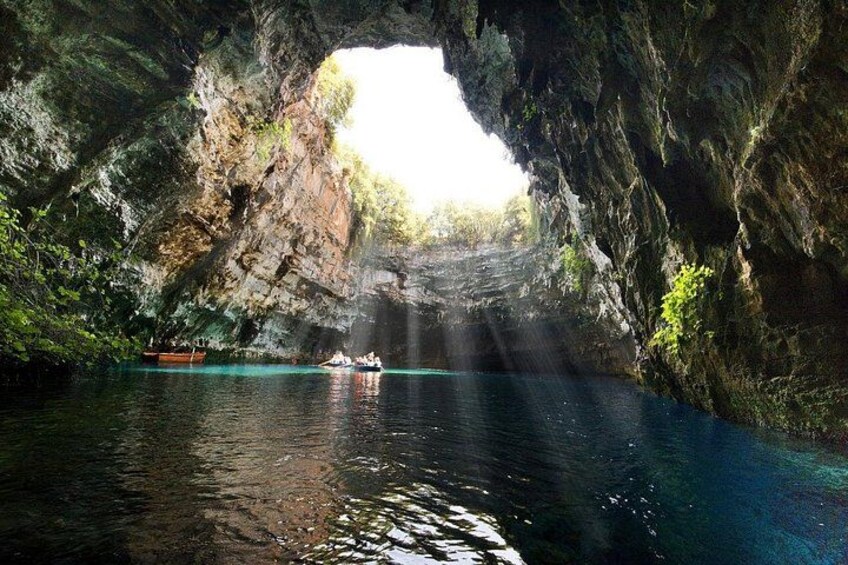 A cave opening with water inside, a boat, and a person kayaking. 2