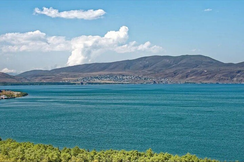 A large body of water with a distant shoreline, mountains, and a clear sky. 3