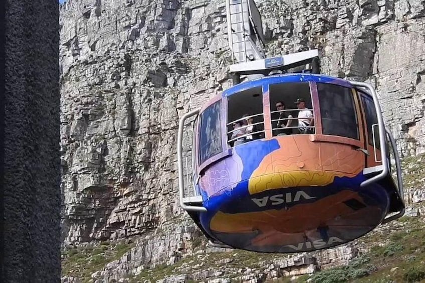 A cable car with passengers, suspended above a rocky cliff. 3