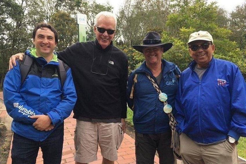 Four people standing on a brick pathway with trees in the background. 3