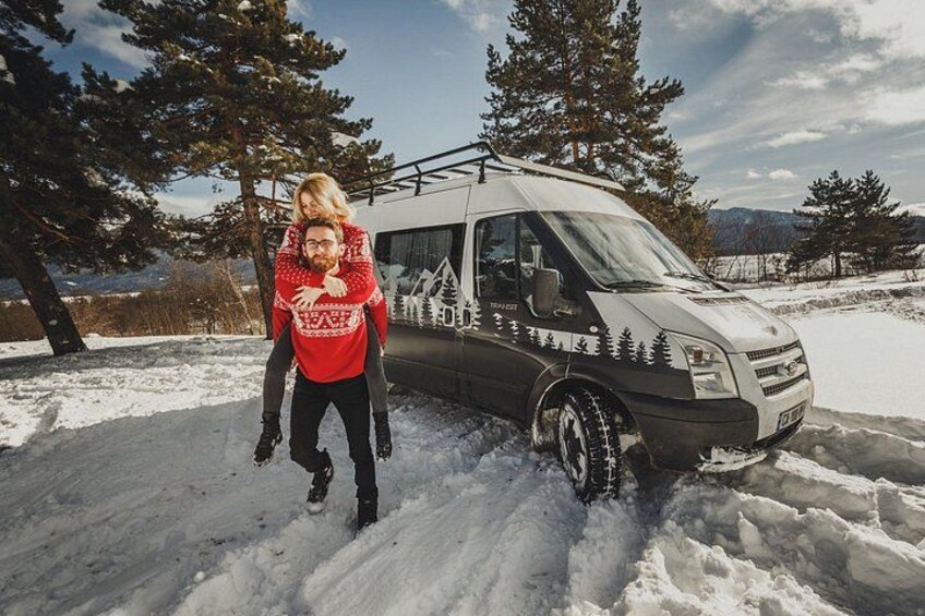 A person carrying another on their back, a snow-covered landscape with trees, and a vehicle with a forest design. 4