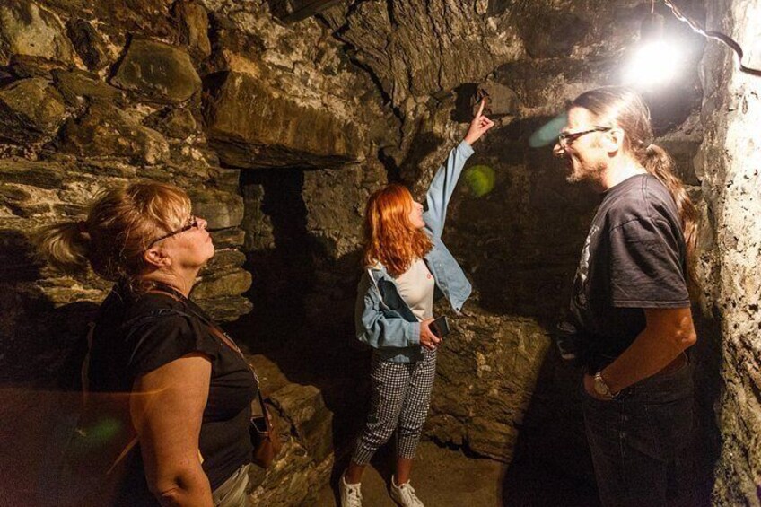 Three people inside a cave with rocky walls and a light source. 5