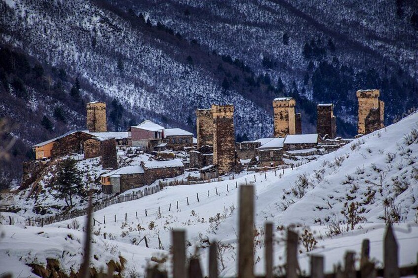 A snow-covered village with stone buildings and a mountainous backdrop. 2