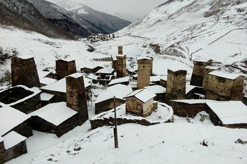 A snow-covered village with stone buildings and a mountainous backdrop. 3