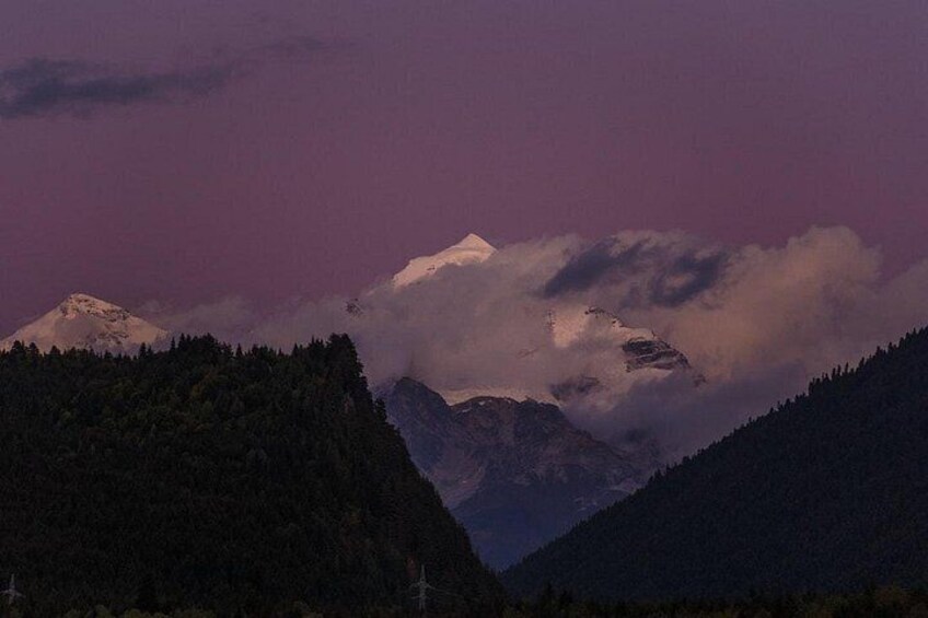 A mountain range with snow-capped peaks and a forested valley. 4