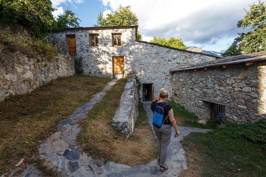 A stone building with a pathway leading to it, surrounded by grass and trees. 4