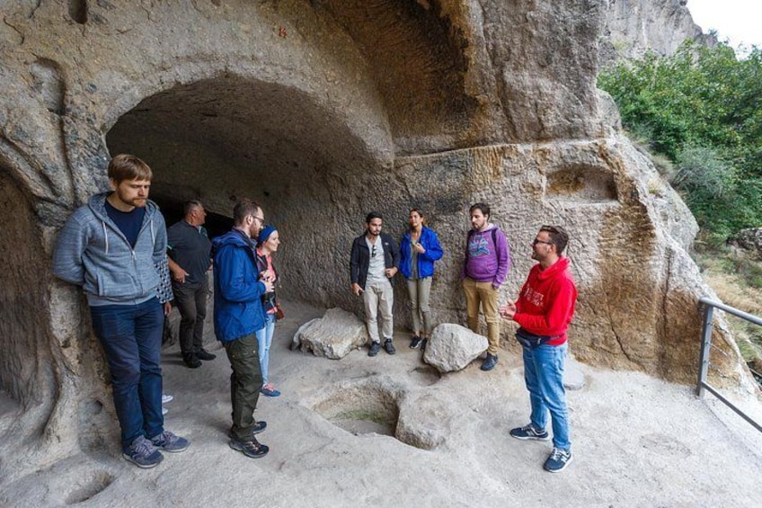 A group of people standing in front of a cave entrance. 4