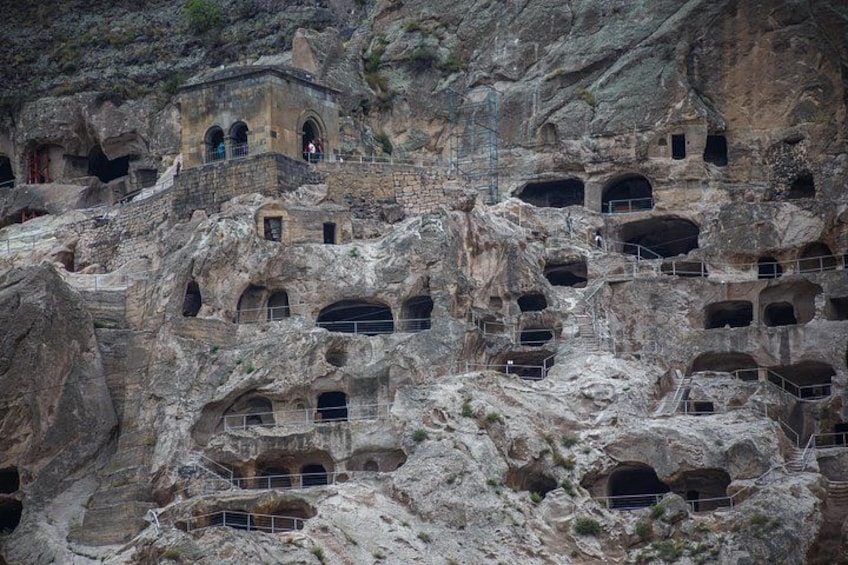 A rock formation with multiple cave dwellings carved into the cliff. 5