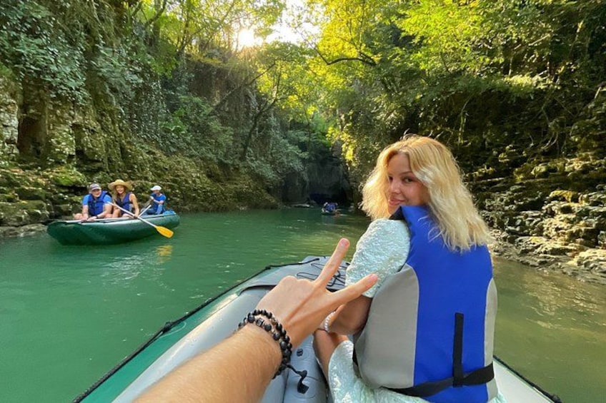 A river with a green boat carrying three people. 1