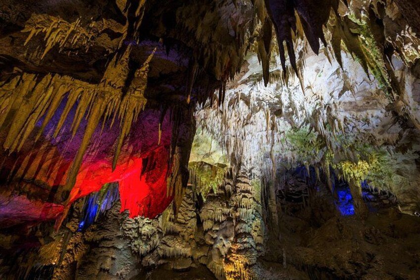 A cave with stalactites and stalagmites, illuminated by colored lights. 2