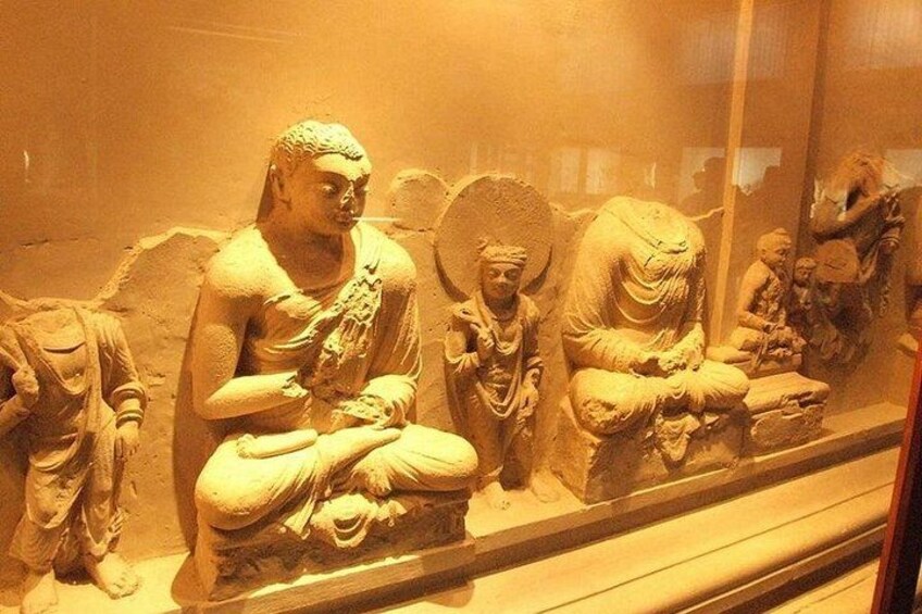 A collection of ancient stone statues in a museum display case. 3