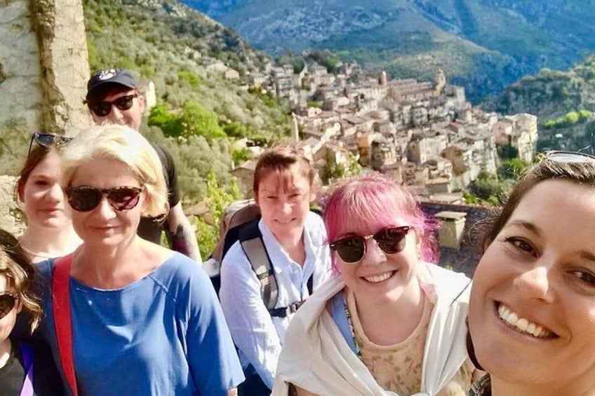 A group of people on a hiking trail with a mountainous village in the background. 5