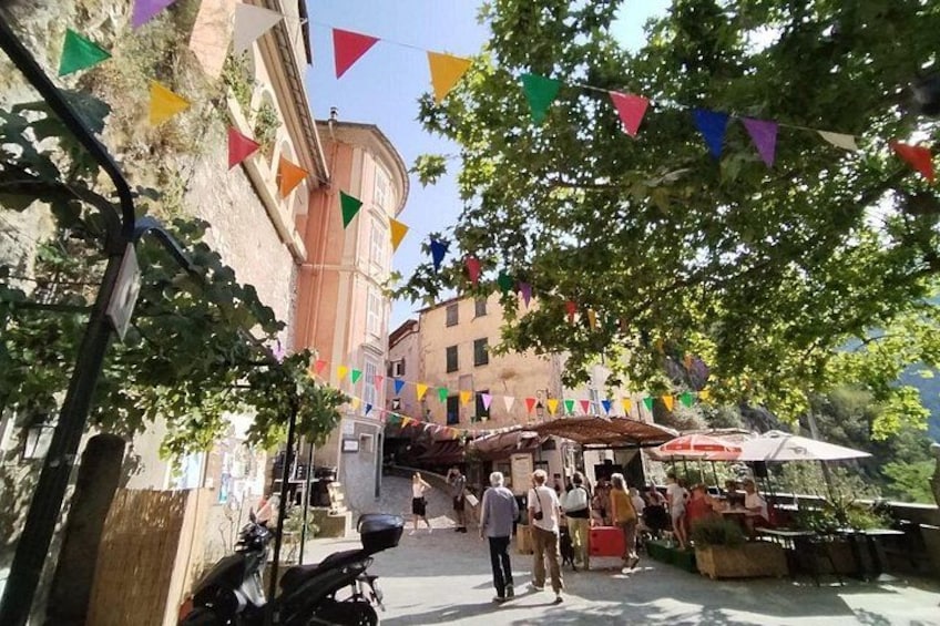 Une rue bordée de drapeaux colorés, un bâtiment avec un coin arrondi, et des gens qui se promènent. 3