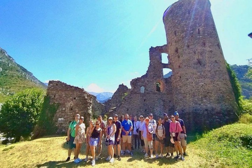 A group of people standing in front of a historical stone structure with ruins. 3