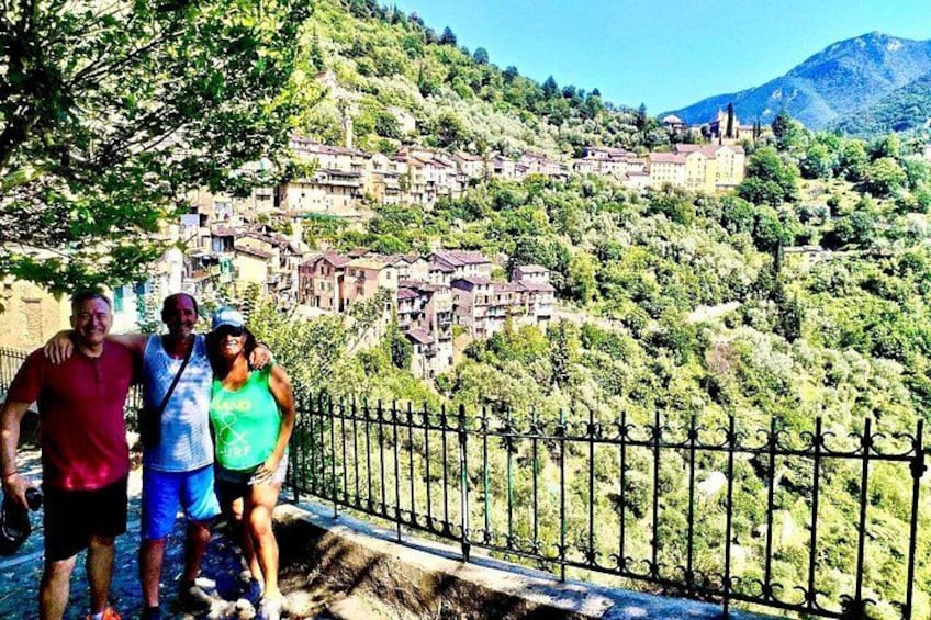 Three people standing on a path with a view of a hillside village. 2