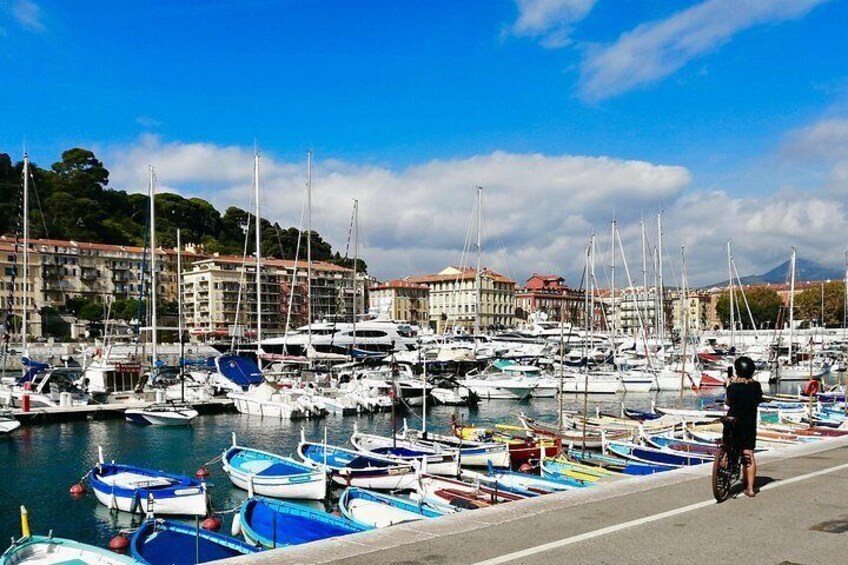 Un puerto deportivo con numerosas embarcaciones amarradas, una persona de pie en el muelle y edificios al fondo. 5