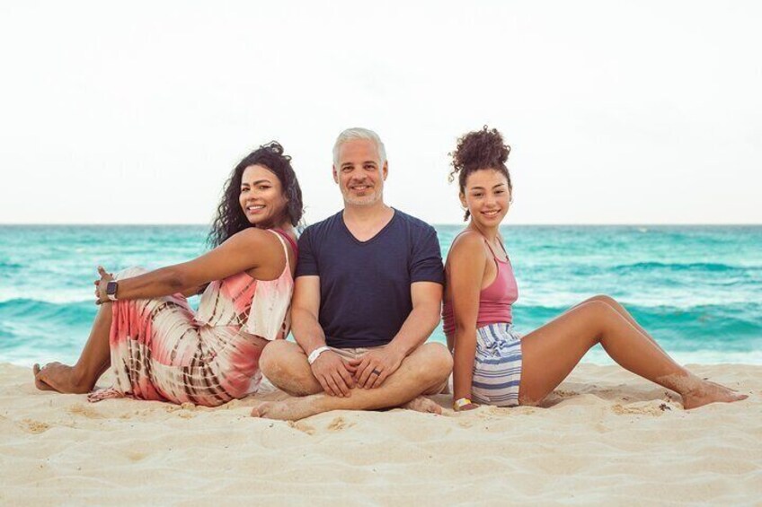 Three people sitting on a sandy beach with the ocean in the background. 1