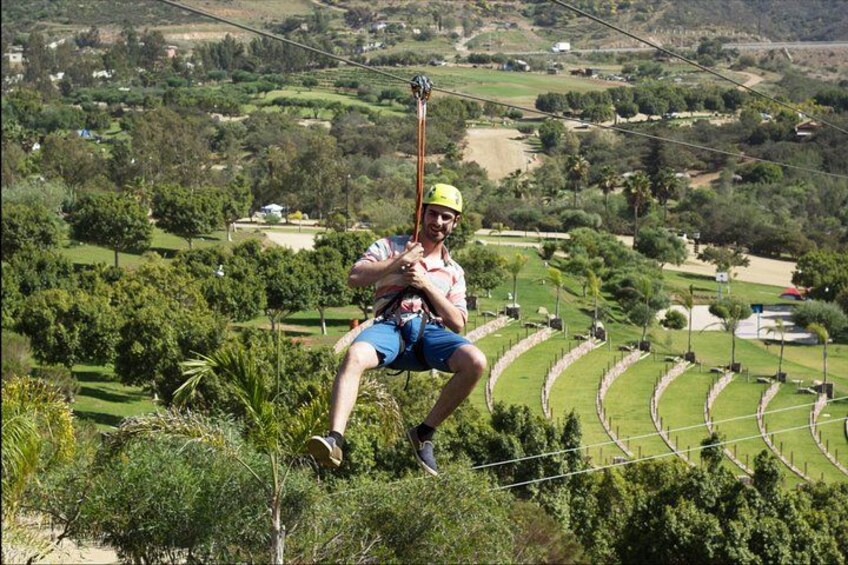 A person zip-lining over a lush green landscape with terraced fields below. 2