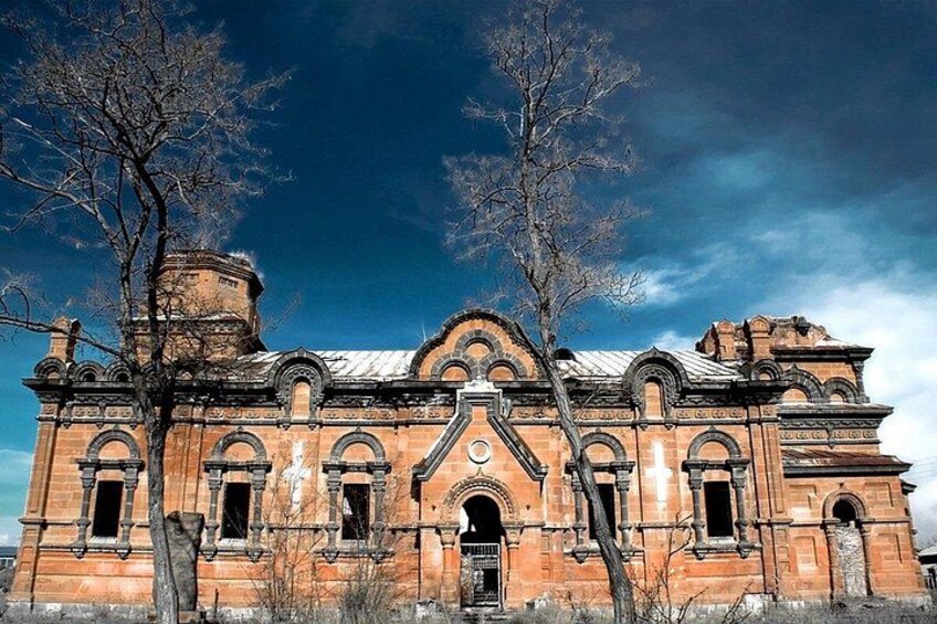 A large, historic brick building with arched windows and a central entrance. 2