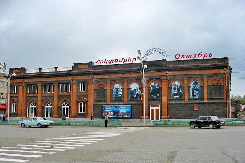 A large building with arched windows and a sign that reads 'Окмабрь'. 3
