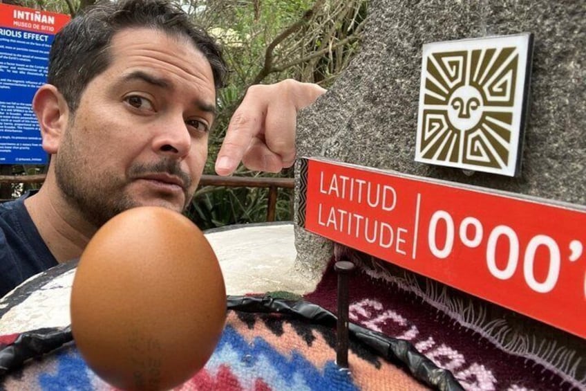 A person pointing at a sign with 'LATITUD LATITUDE 0º00'.' 1