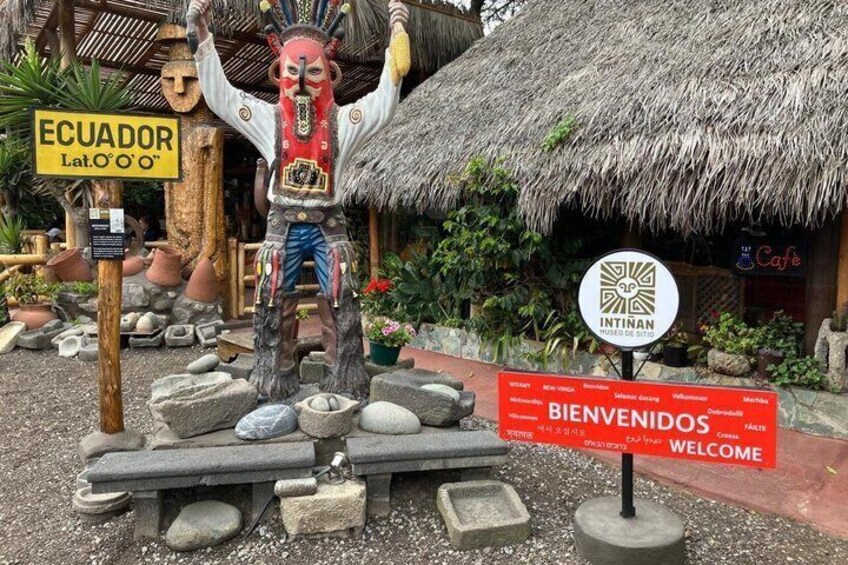 A traditional Ecuadorian statue, a thatched-roof hut, and a welcome sign. 5