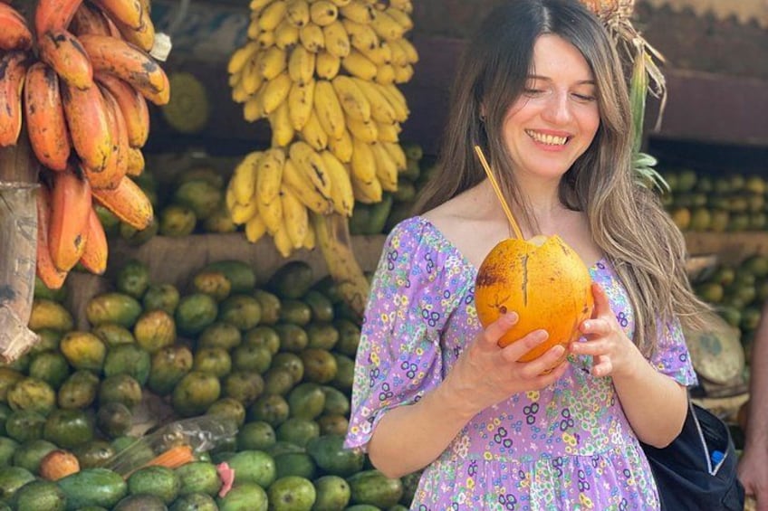 Una persona sostiene un coco con una pajita, rodeada de diversas frutas y verduras. 3