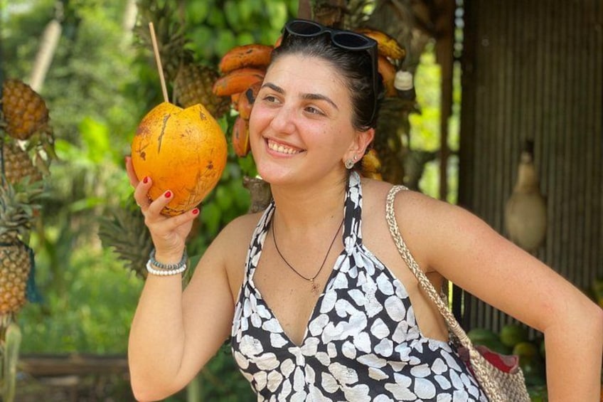 Una persona sosteniendo un coco con un fondo tropical. 2