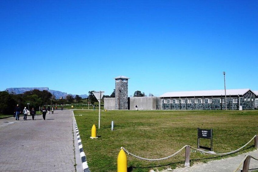 Un grand bâtiment doté d’une tour, d’une zone herbeuse et d’une route où l’on voit des gens se promener. 4