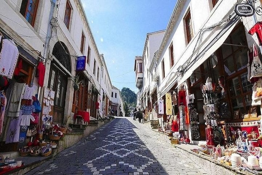 A cobblestone street lined with shops displaying various goods. 3
