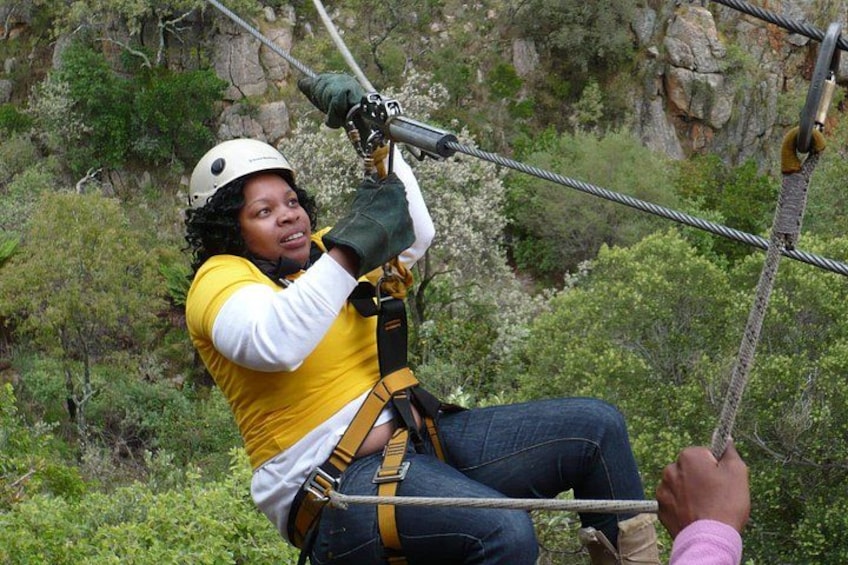 A person zip-lining through a forested area with rocky cliffs in the background. 3