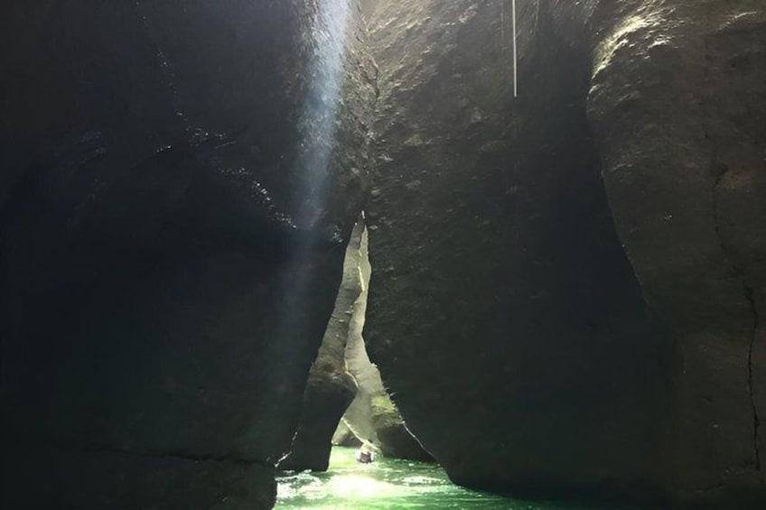 A cave with a narrow passage and a pool of water at the end. 4