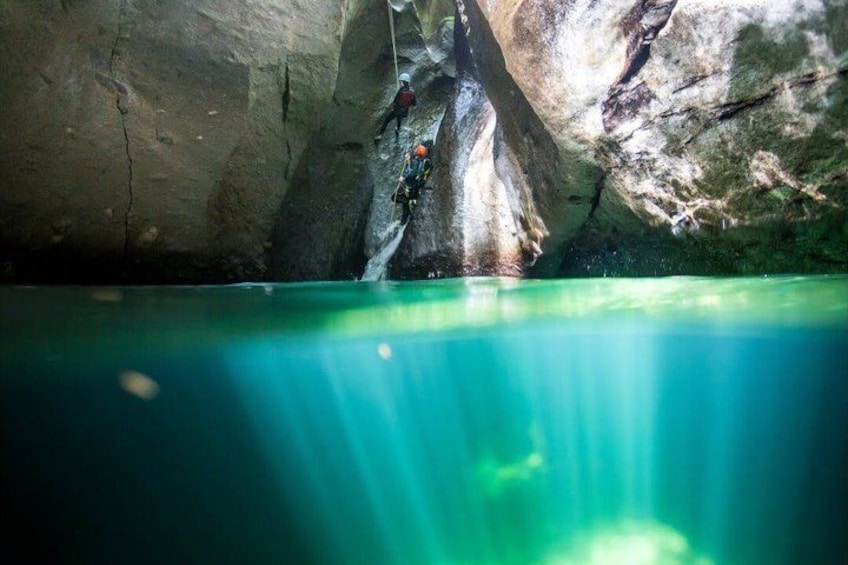 A person climbing a rock formation with a rope, water below, and a cave interior. 5