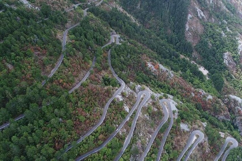Een kronkelende bergweg, omgeven door dicht bos. 4