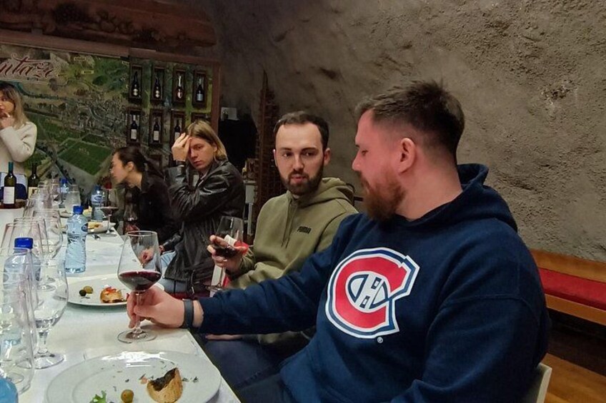 A group of people seated at a table with wine glasses and bottles. 3