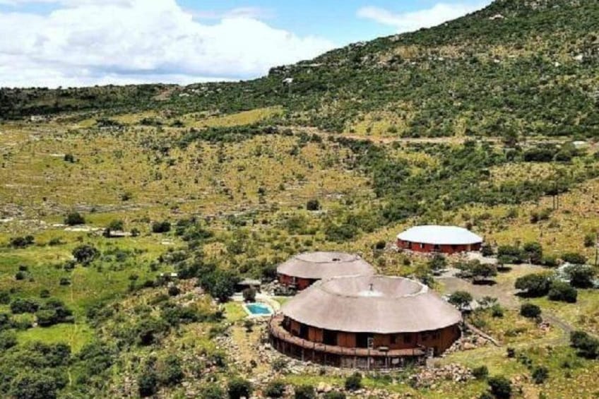 Paisaje rural con dos construcciones circulares cubiertas de tierra y una pequeña piscina. 3