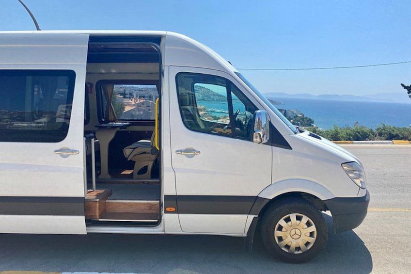 En vit skåpbil står parkerad vid en väg, med en vacker utsikt över havet och kullarna i bakgrunden. 1