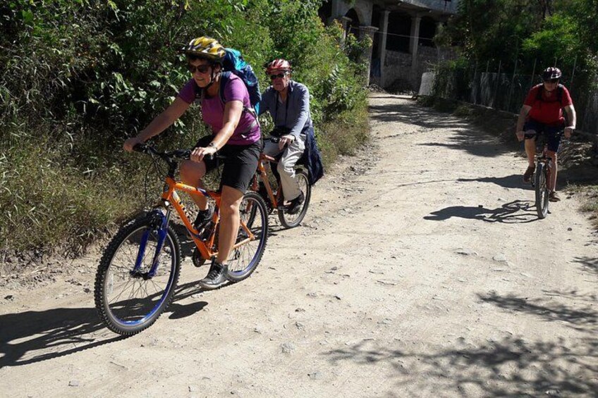 A group of cyclists on a dirt path surrounded by greenery. 2