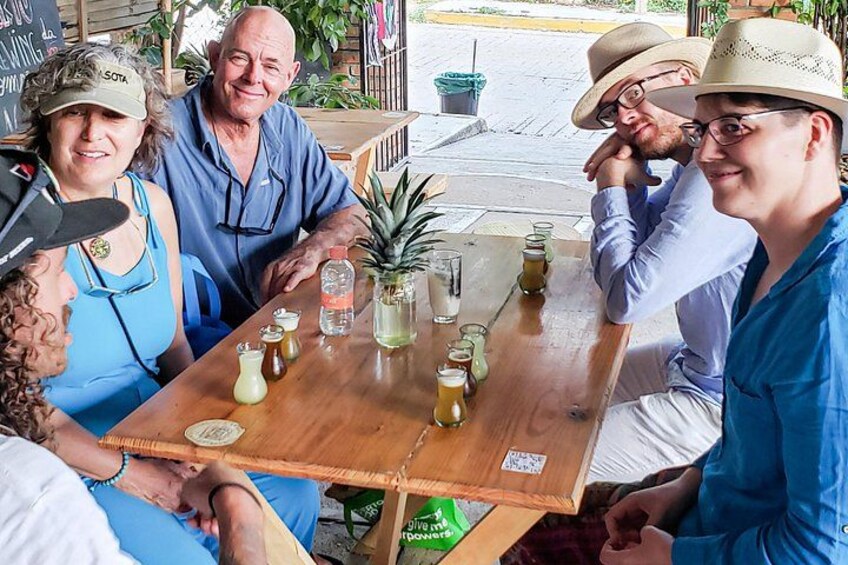 Un gruppo di persone sedute attorno a un tavolo di legno, con bevande e un'ananas. 5