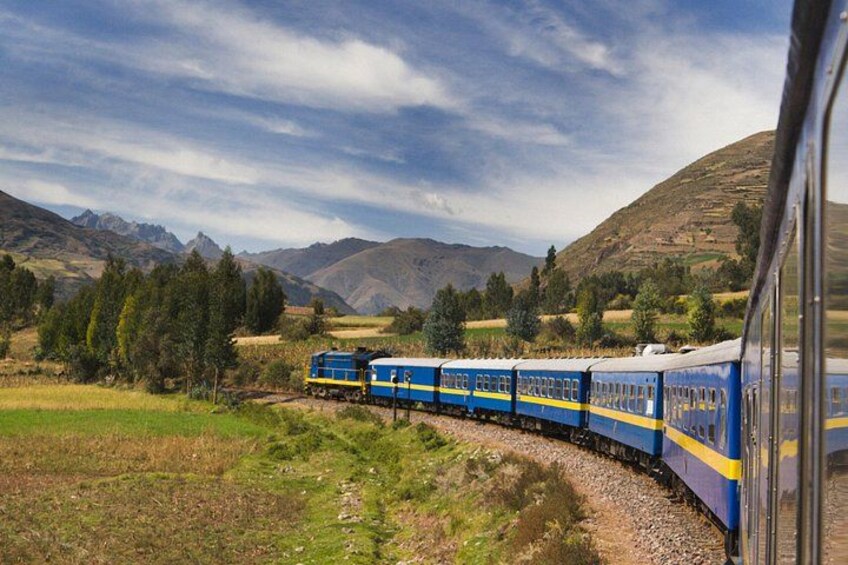 A train traveling through a mountainous landscape with green fields and trees. 2