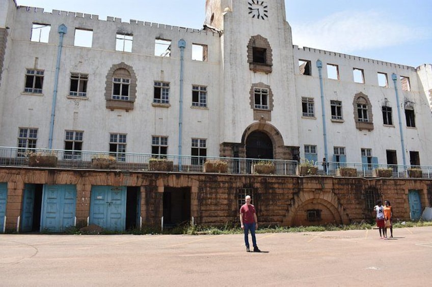 Un edificio grande e histórico con una torre de reloj, múltiples ventanas y un área pavimentada en el frente. 5