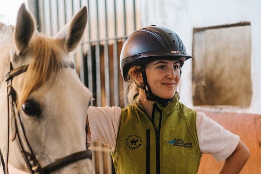 Eine Person mit Helm und grüner Weste steht neben einem Pferd. 4